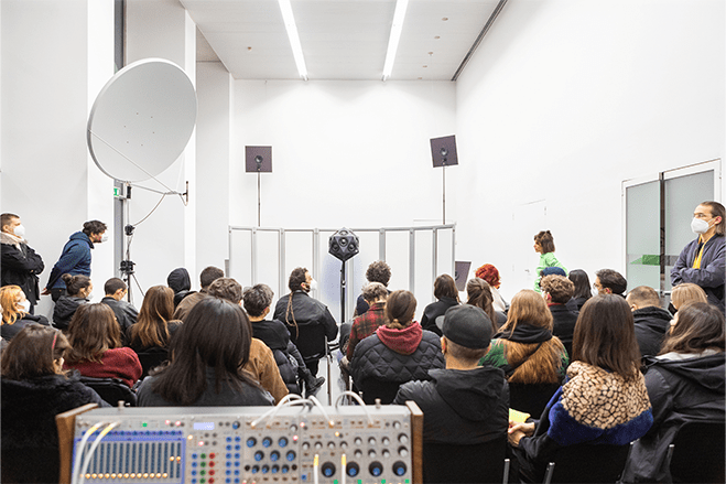 Visitors in a small room sitting in front of the IKO speaker system